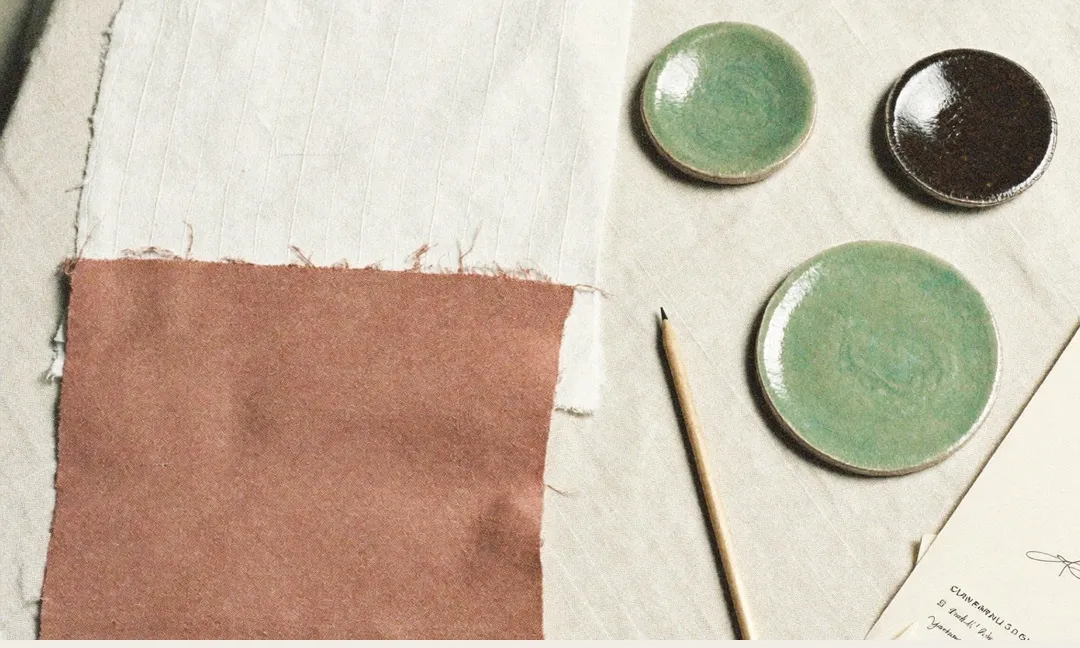 Muestras de lino y terracota junto a platos de cerámica verde salvia: una paleta 60-30-10
